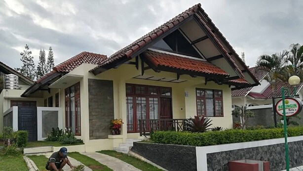 A house with a tiled roof, a stone wall, and a paved front yard. - Villa Private Puncak (Cipanas)
