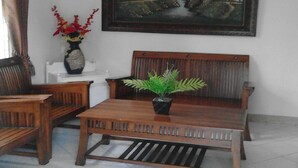Un salon avec un canapé en bois, une table basse et un tableau accroché au mur.