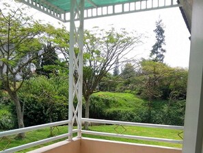 A covered balcony with a view of a garden and trees. - Villa Puncak Resort (Cipanas)