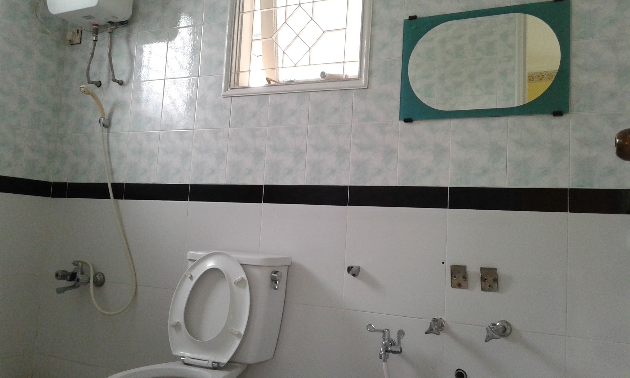 A bathroom with a toilet, a sink, a mirror, and a window.