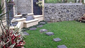 Un jardin bien entretenu, agrémenté d’un mur en pierre, d’un petit élément décoratif aquatique et d’une variété de plantes.