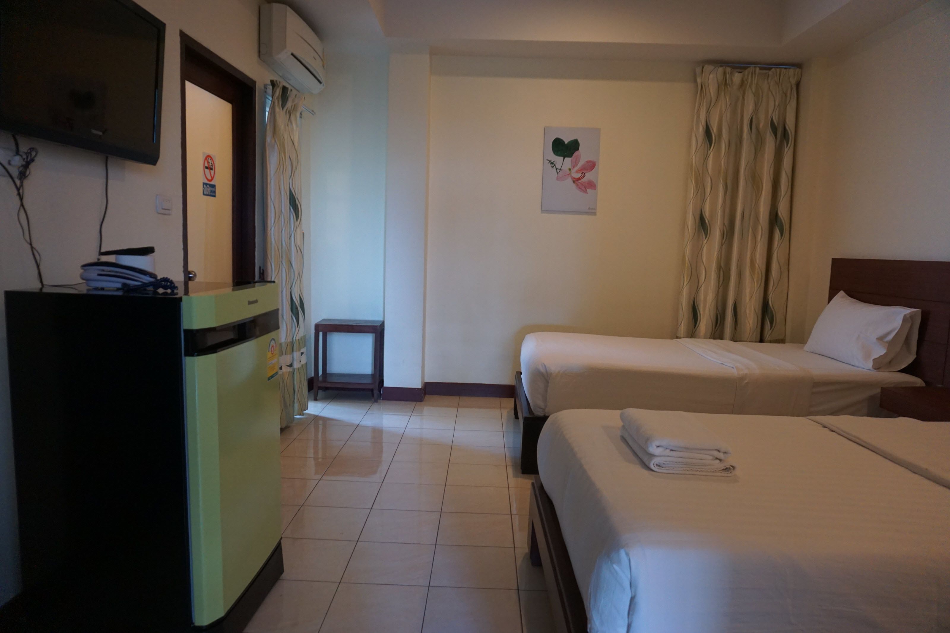 Habitación de hotel con dos camas, un escritorio, un televisor y una mesita.