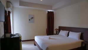 Une chambre d’hôtel équipée d’un lit, d’un bureau, d’une lampe et d’un climatiseur fixé au mur.