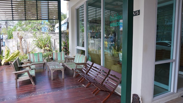 Un espace extérieur abrité, aménagé avec du mobilier en bois et offrant une vue sur la rue grâce à de grandes fenêtres.
