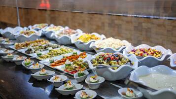 Buffet com diversos pratos dispostos em tigelas e pratos brancos.