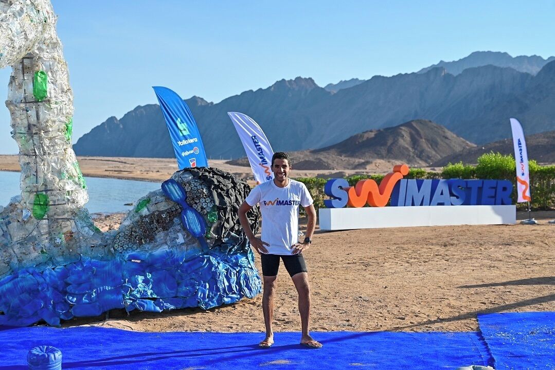 Una persona de pie sobre una esterilla azul, con un letrero que dice "SWIMMASTER" al fondo.