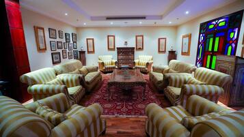 A room with striped sofas arranged around a central coffee table, framed pictures on the walls, and a stained glass window.