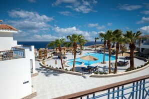 A resort pool area with palm trees, lounge chairs, and a view of the ocean. - Ecotel Dahab Bay View Resort (Dahab)