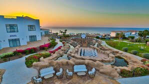 Un resort con zona de piscina, mobiliario exterior y vistas al mar.