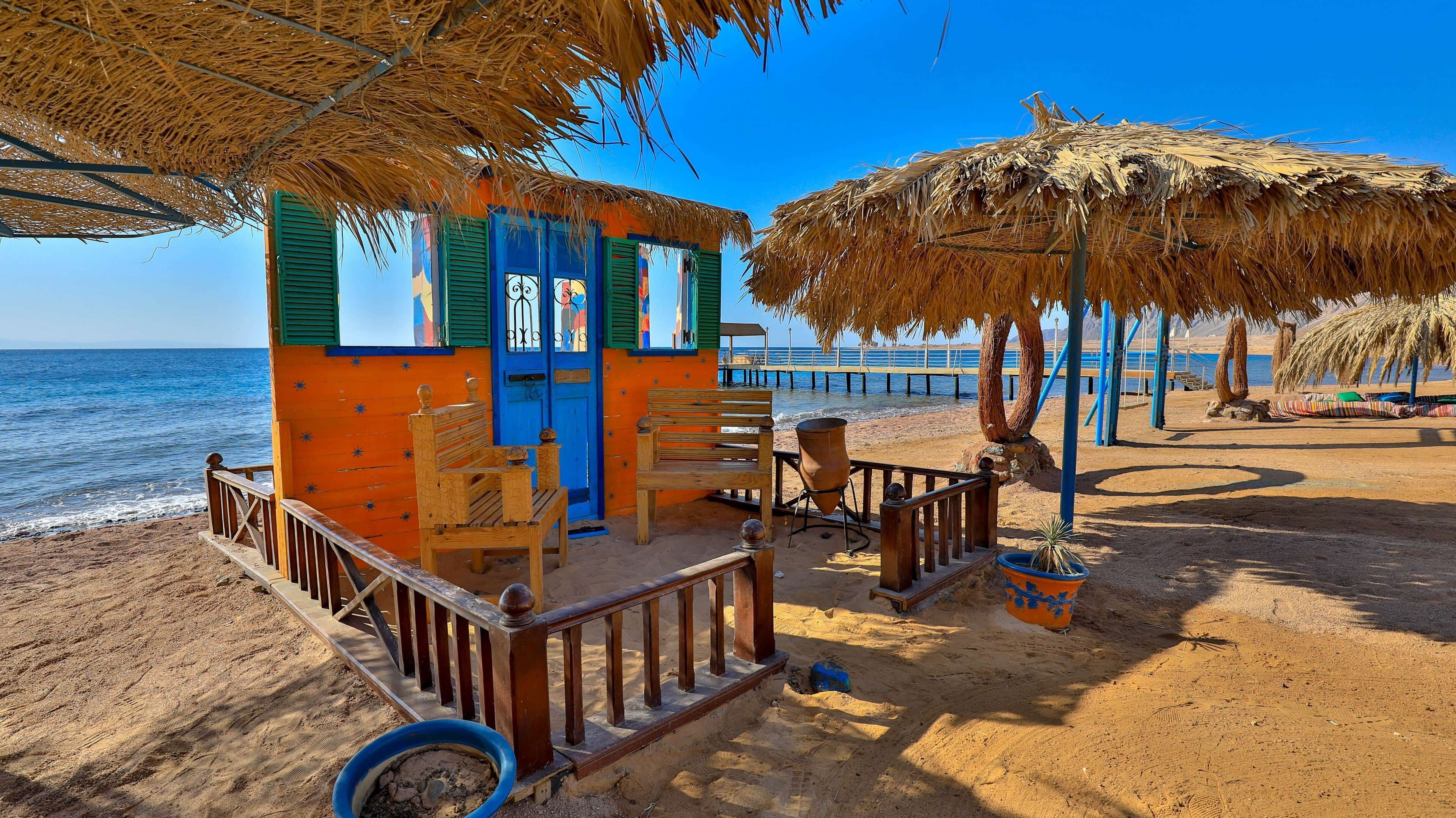 A beachside structure with a wooden bench, a table, and a potted plant.
