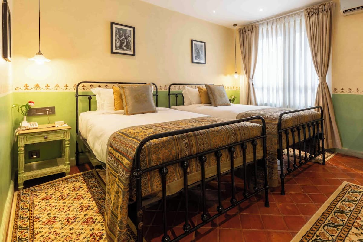 Una habitación con dos camas, una mesita de noche con teléfono y una alfombra estampada.