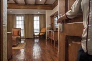 A wooden door with a brass handle, a wooden floor, a chair, a table, and a window with curtains.