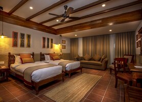 Una habitación de hotel con dos camas, un sofá, un escritorio y un ventilador de techo.