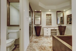 Une salle de bain moderne équipée de toilettes, de deux lavabos, d’un meuble-lavabo et d’un grand miroir.