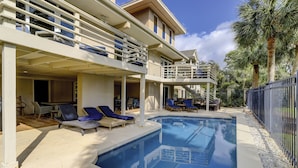 Une maison à deux étages dotée d’une piscine, d’un espace salon extérieur et d’un patio couvert.