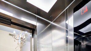 An elevator with a metallic finish, a control panel with buttons, and a checkered floor pattern. - Hotel Keos (Sarandë)