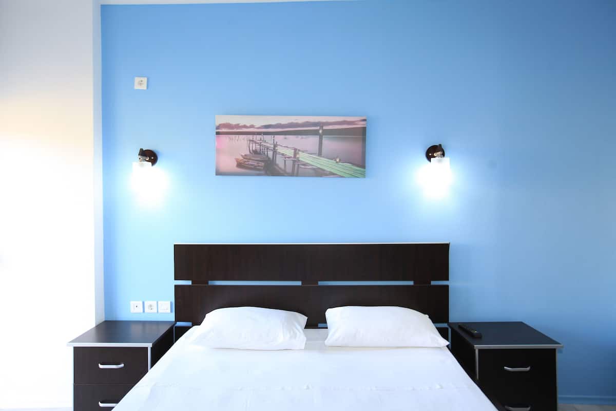 A bedroom with a bed, two bedside tables, a nightstand, and a wall-mounted painting.