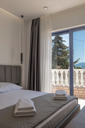 Quarto com cama, cortinas e vista para o exterior.