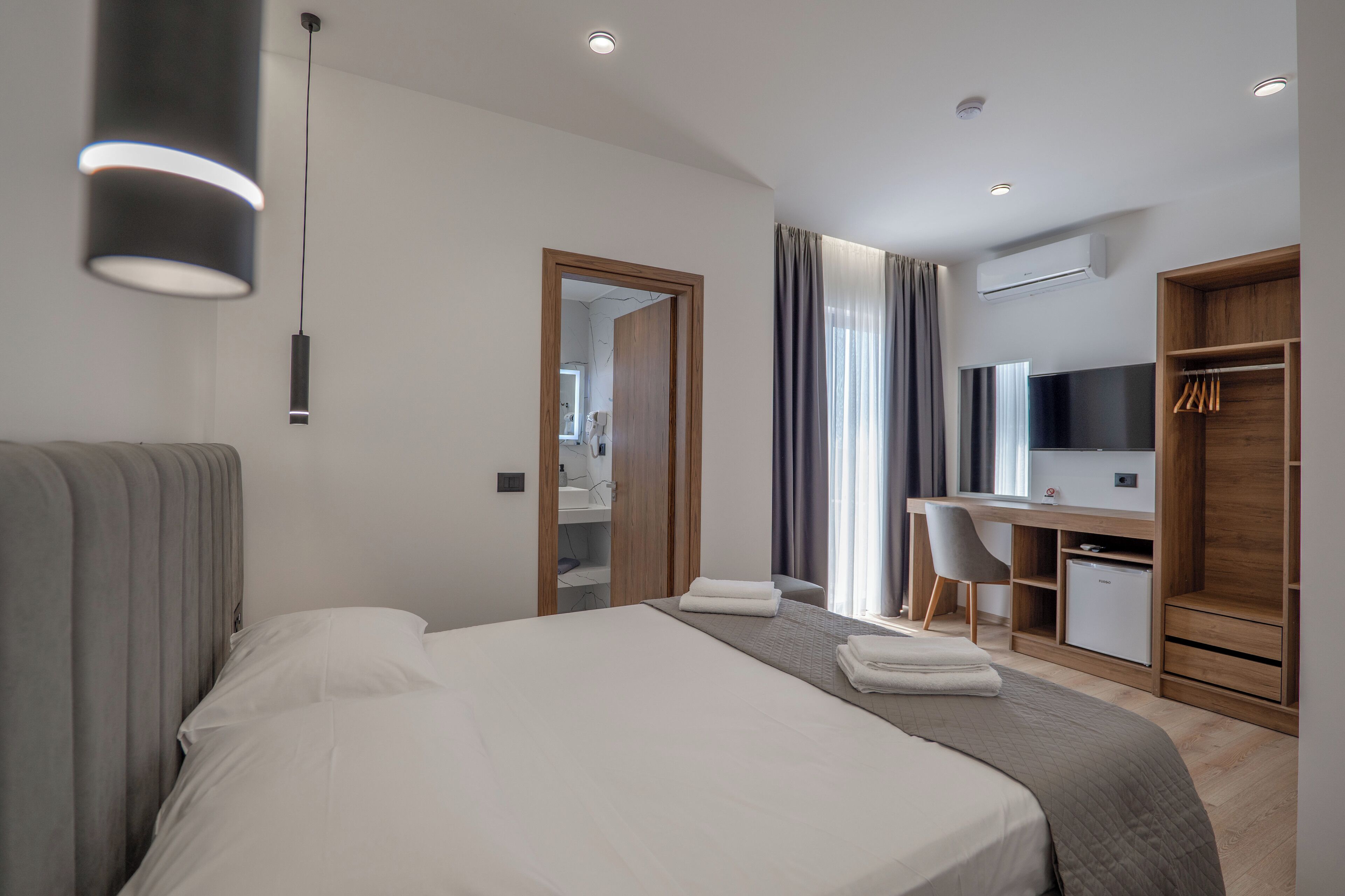 Ein modernes Hotelzimmer mit einem großen Bett, einem Schreibtisch, einem Stuhl und einem Kleiderschrank.