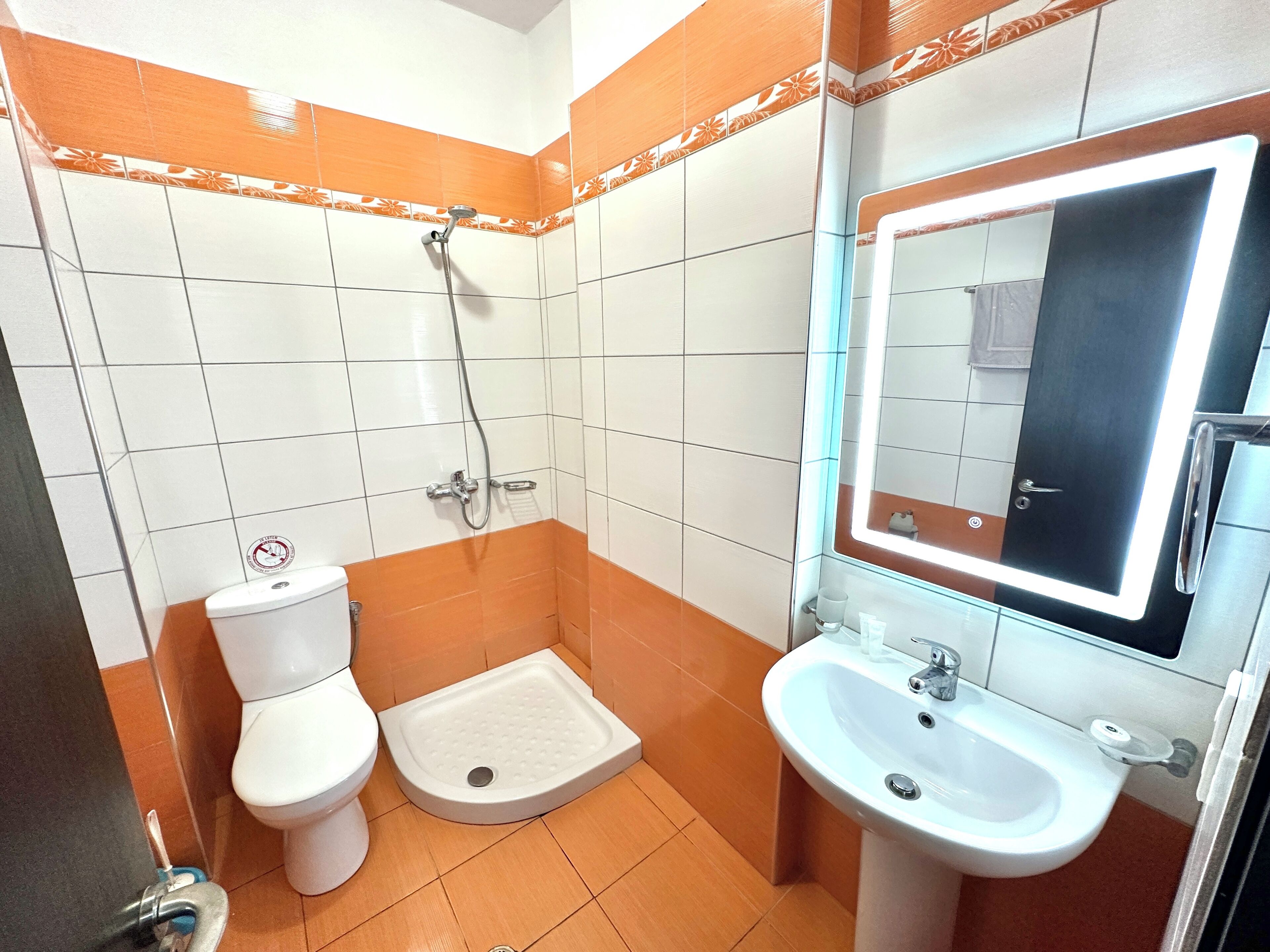 A bathroom with a toilet, shower, and sink.