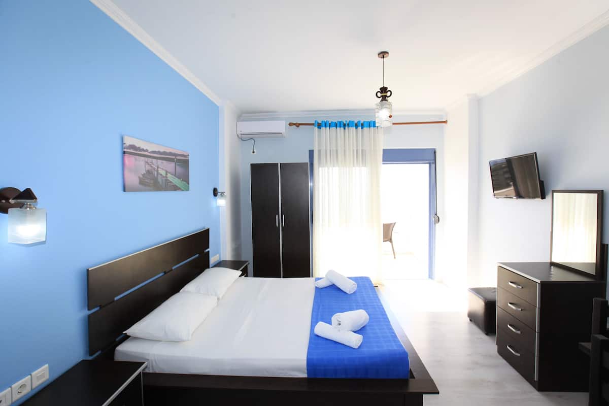 A hotel room with a bed, a desk, a chair, a TV, and a window with curtains.