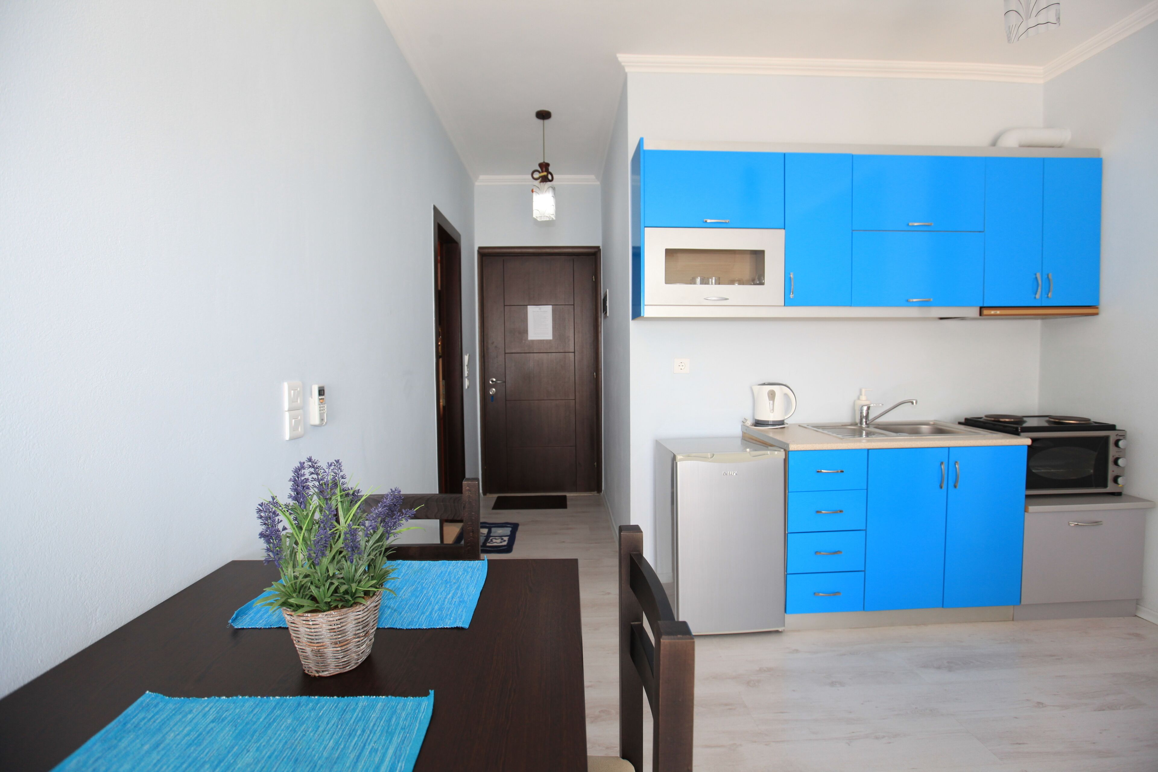 Une cuisine de taille réduite avec des meubles bleus, un four à micro-ondes, une cuisinière et un réfrigérateur.