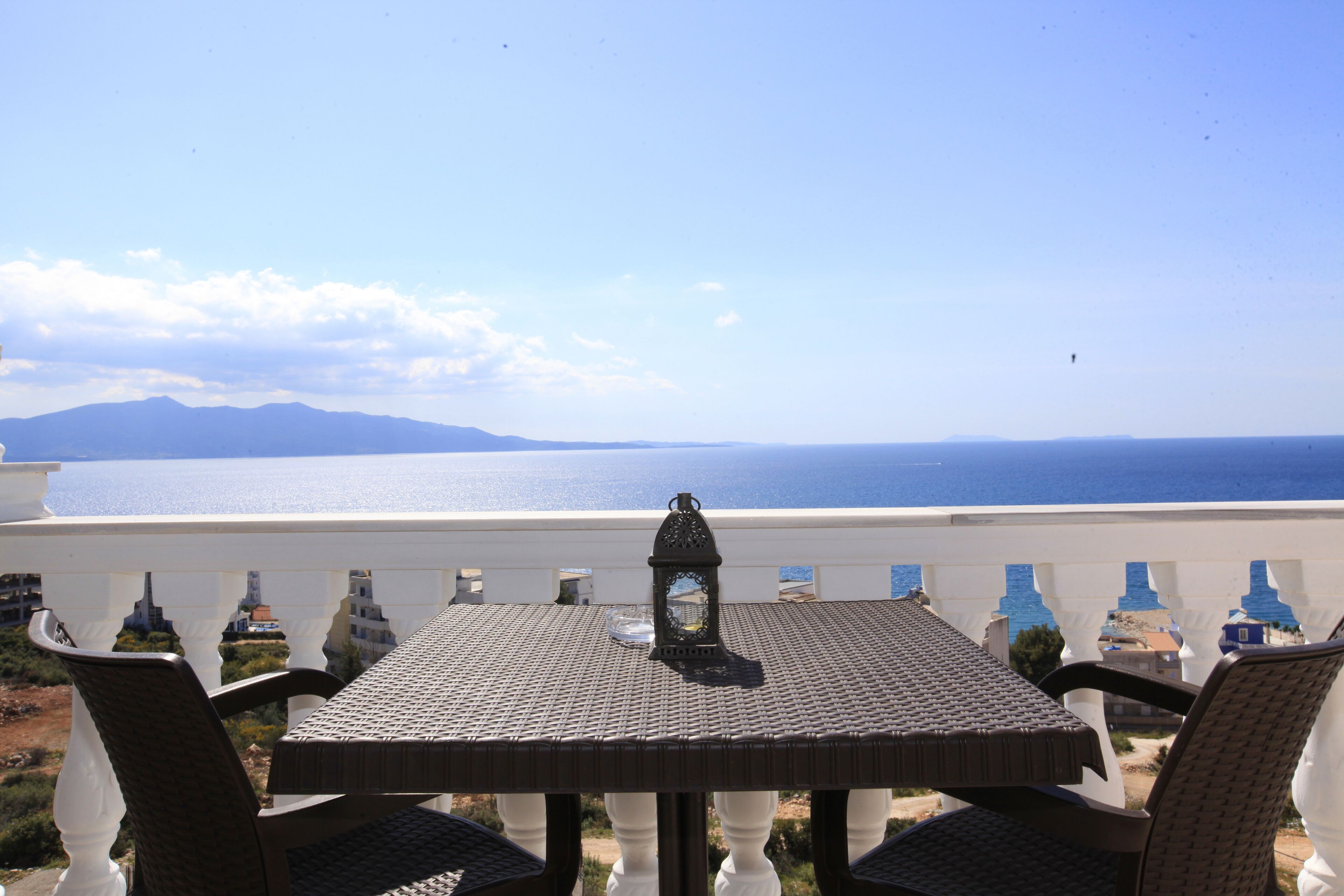 A balcony with a table and chairs overlooking a coastal view.