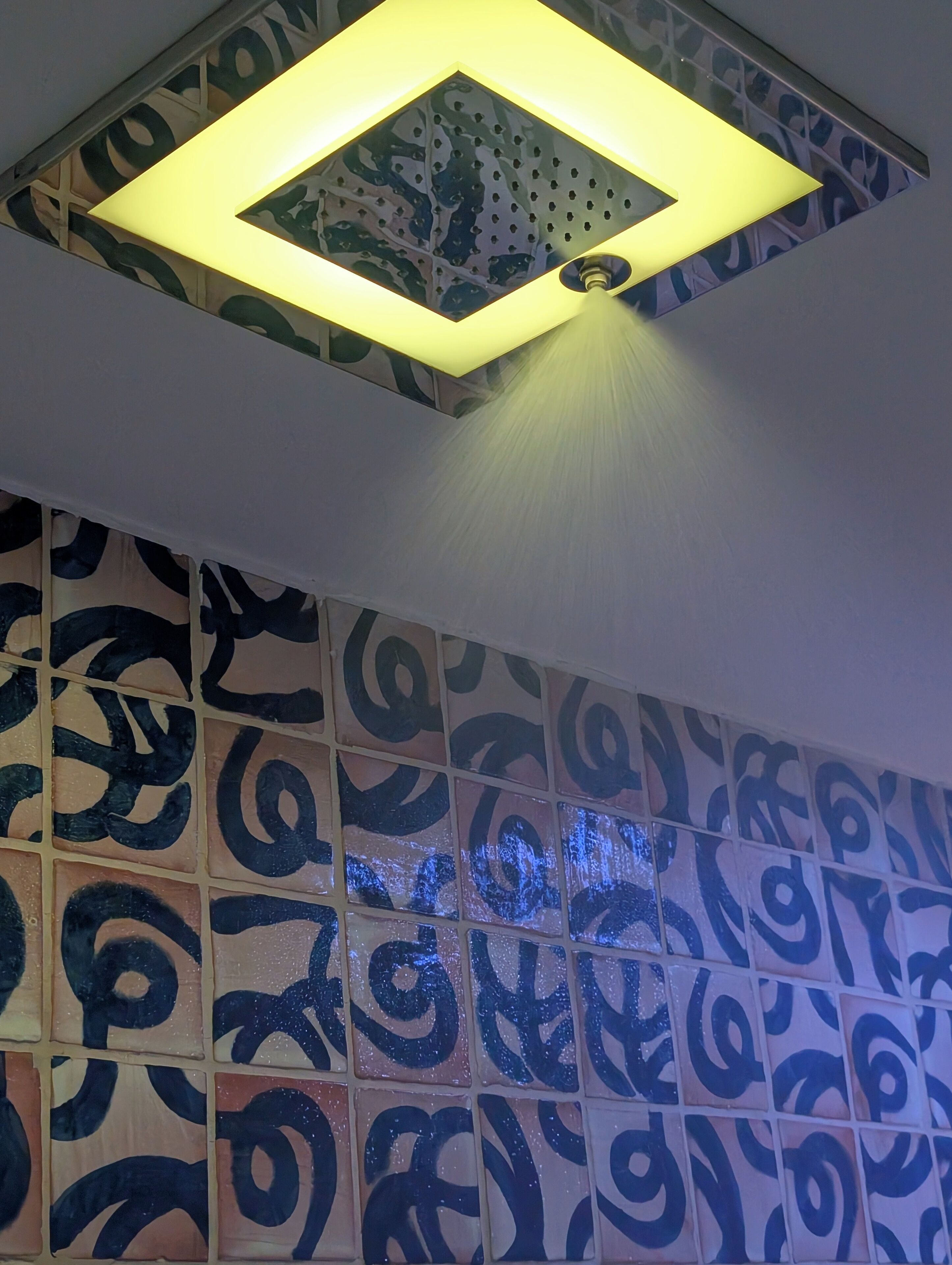 Un soffitto con un portalume quadrato e una parete decorata sotto.
