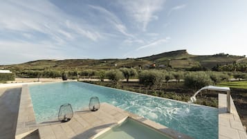 Una piscina al aire libre, sombrillas, sillones reclinables de piscina