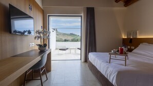 Habitación de hotel con cama, escritorio, televisor y vistas al exterior.