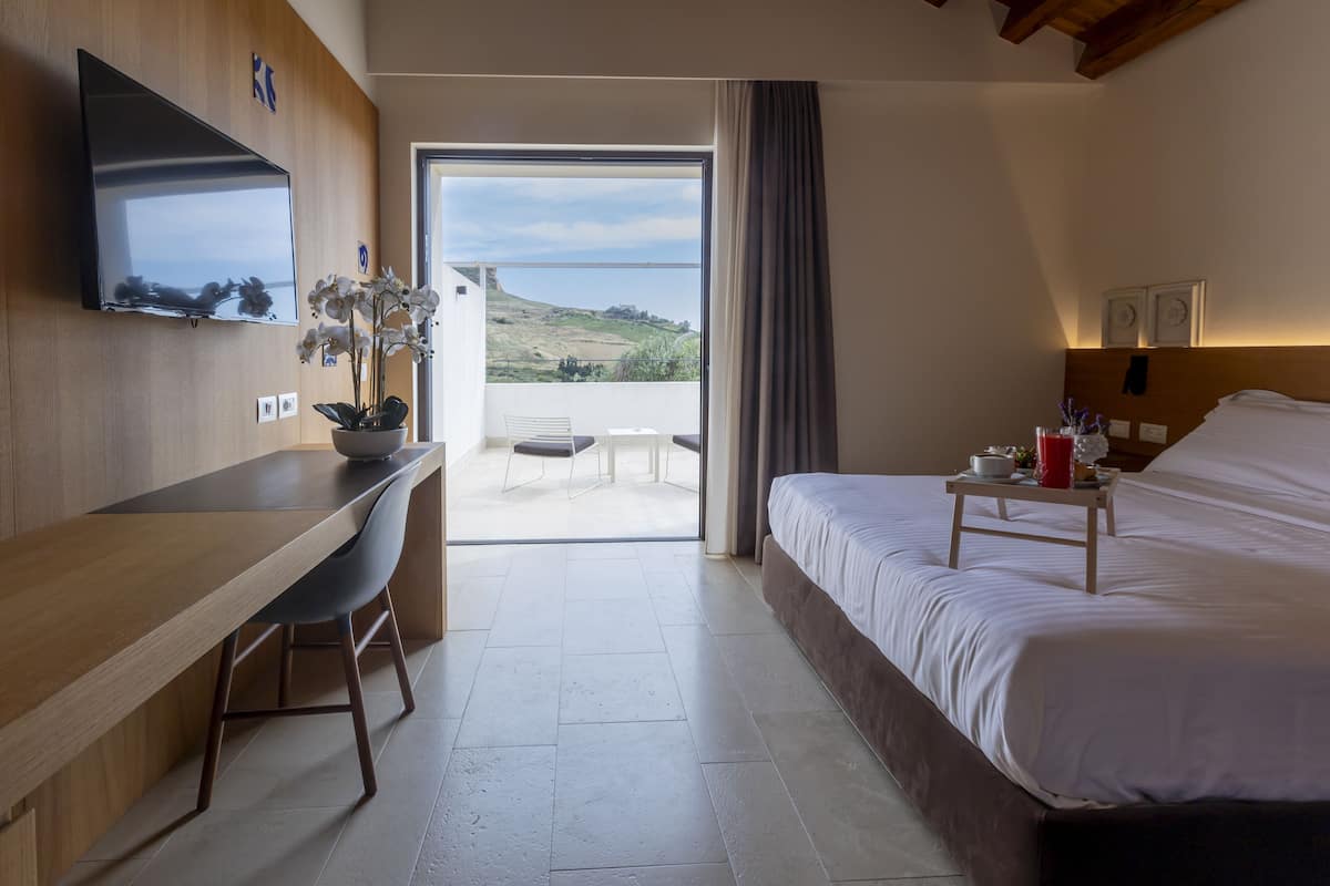 Une chambre d’hôtel avec un lit, un bureau, une télévision et une vue sur l’extérieur.