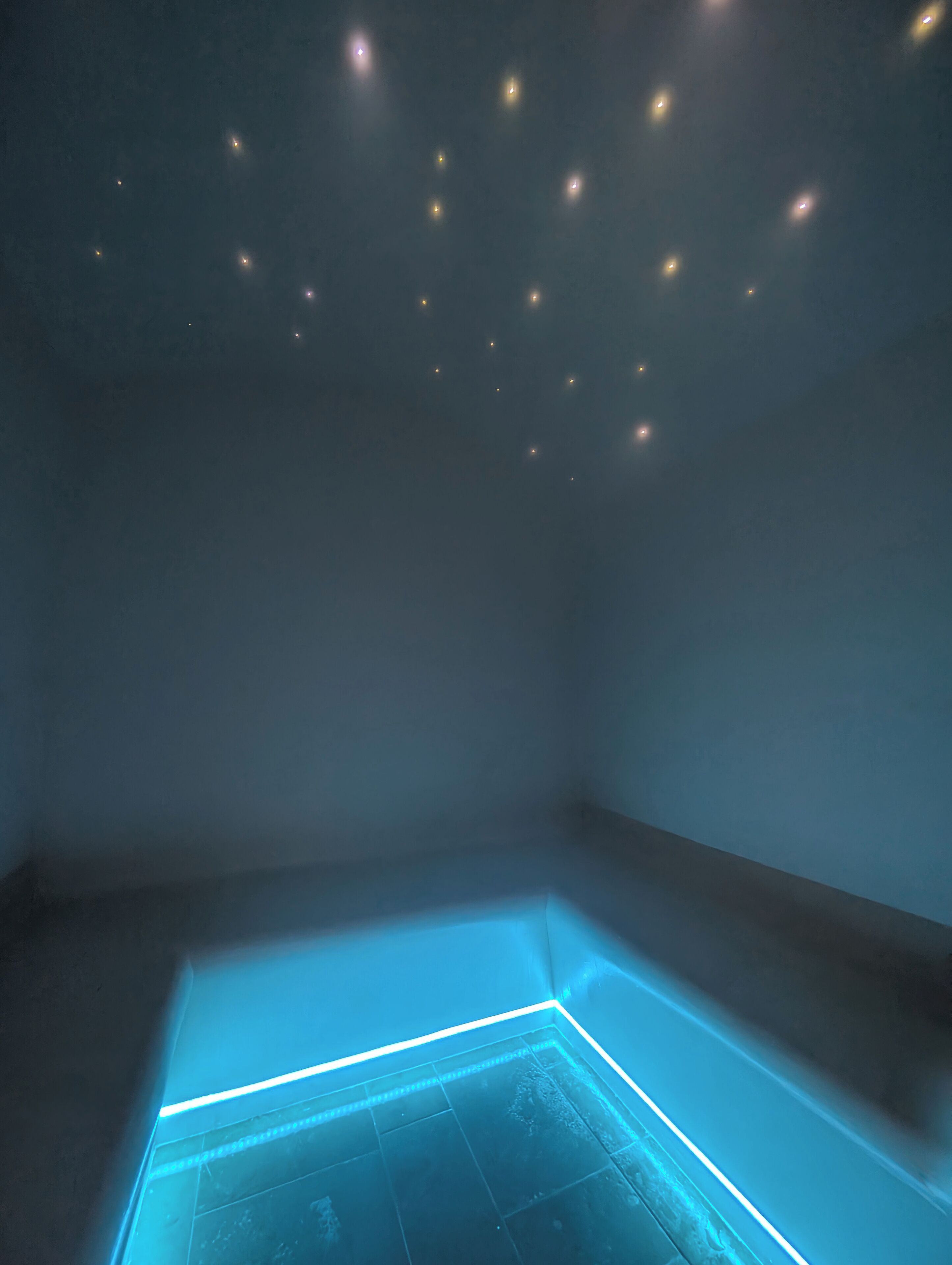 A room with a geometric light installation on the floor and small lights on the ceiling.