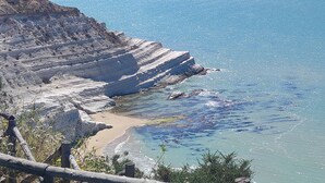 Un paisaje costero con un acantilado rocoso y una playa de arena.