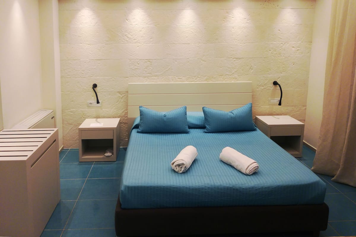 Une chambre d’hôtel avec un lit, deux tables de chevet et un radiateur.