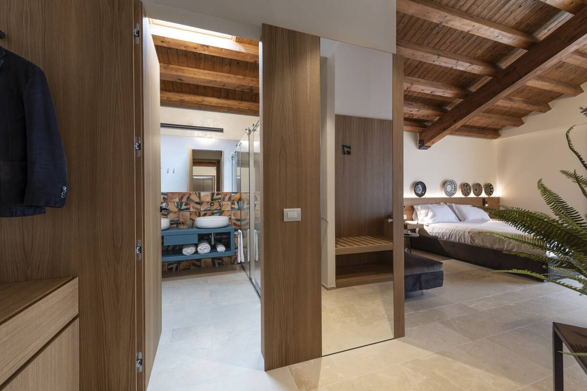 Une chambre à coucher moderne avec un plafond en bois, un lit, une table de chevet et un grand miroir.