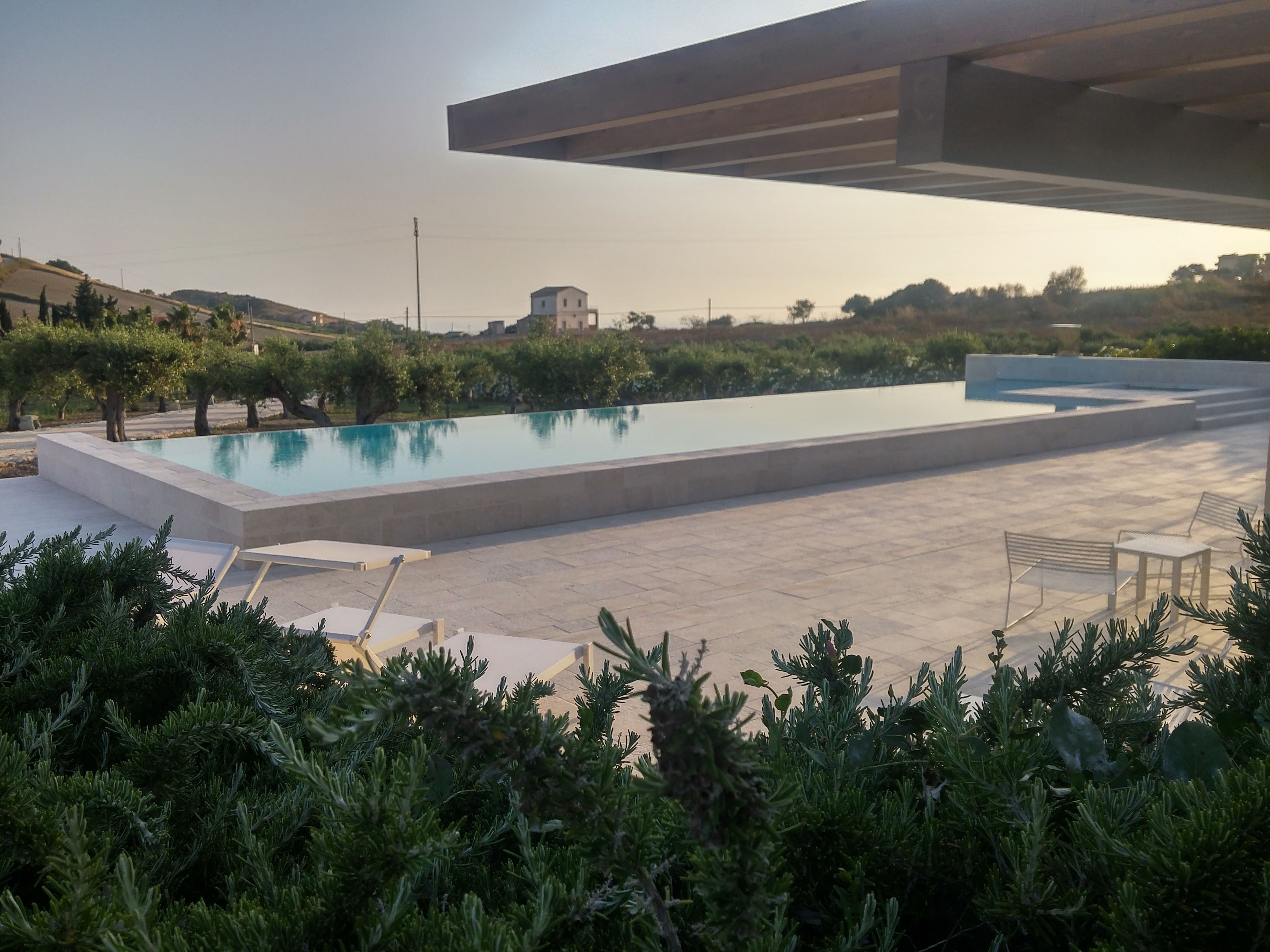 A modern outdoor pool area with a clear view of the surrounding landscape, including distant buildings and a clear sky.