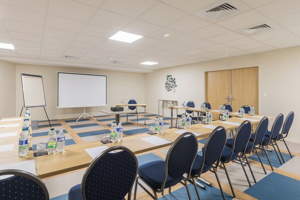 A conference room with a large table, chairs, water bottles, and a projector screen.