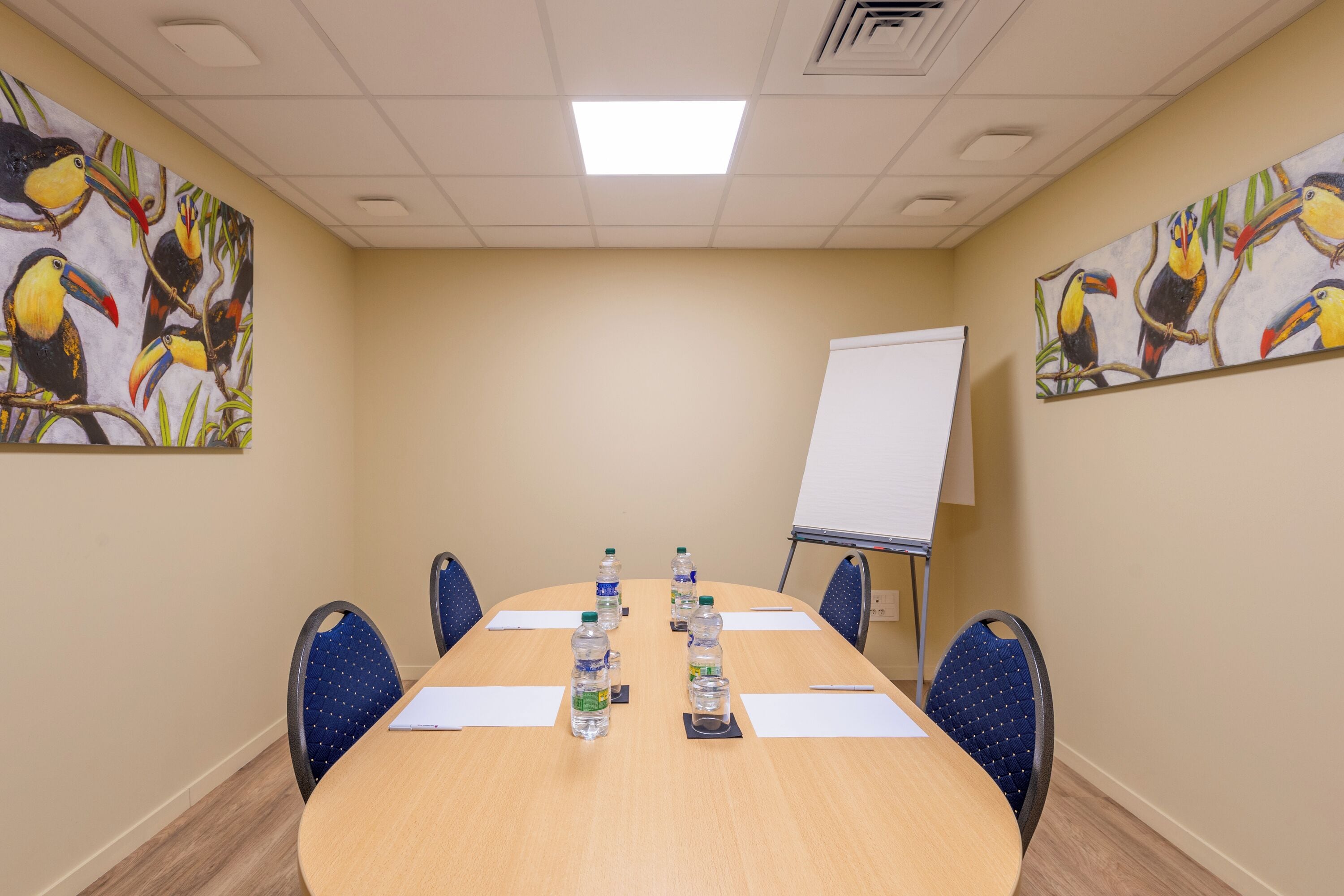 A conference room with a long table, chairs, water bottles, and a whiteboard.