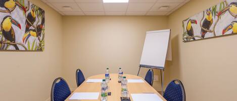 A conference room with a long table, chairs, water bottles, and a whiteboard.