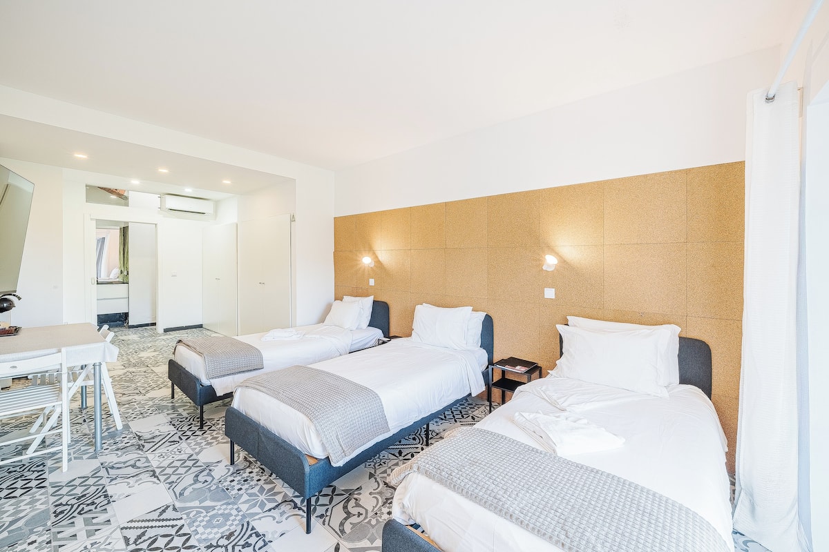 Habitación de hotel con tres camas, un escritorio y piso con diseño.