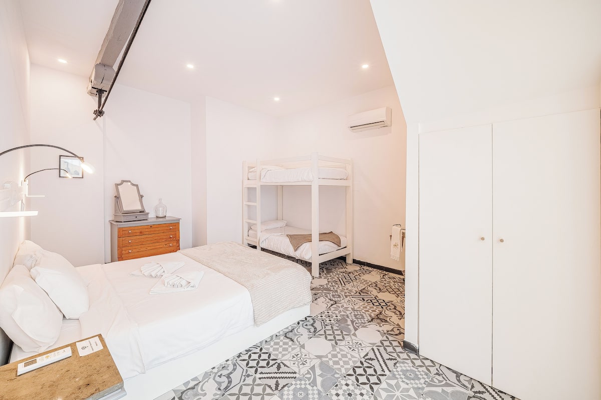 Un dormitorio con una cama litera, una mesita de noche, un aparador y un armario.