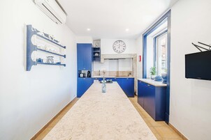 Una cocina moderna con armarios azules, una isla central, un reloj y un televisor de pantalla plana.