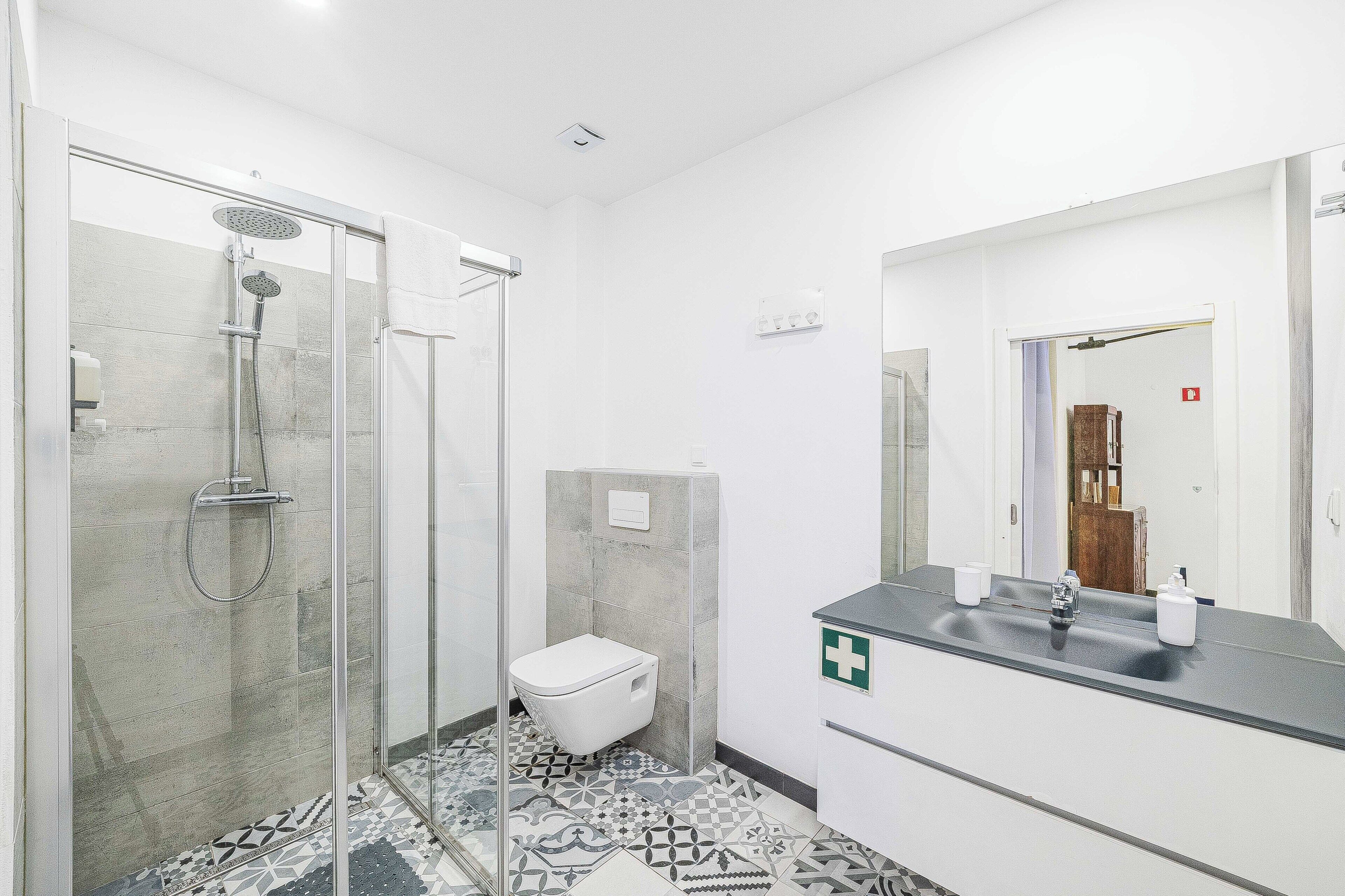 Un baño con ducha, inodoro, lavamanos y espejo.
