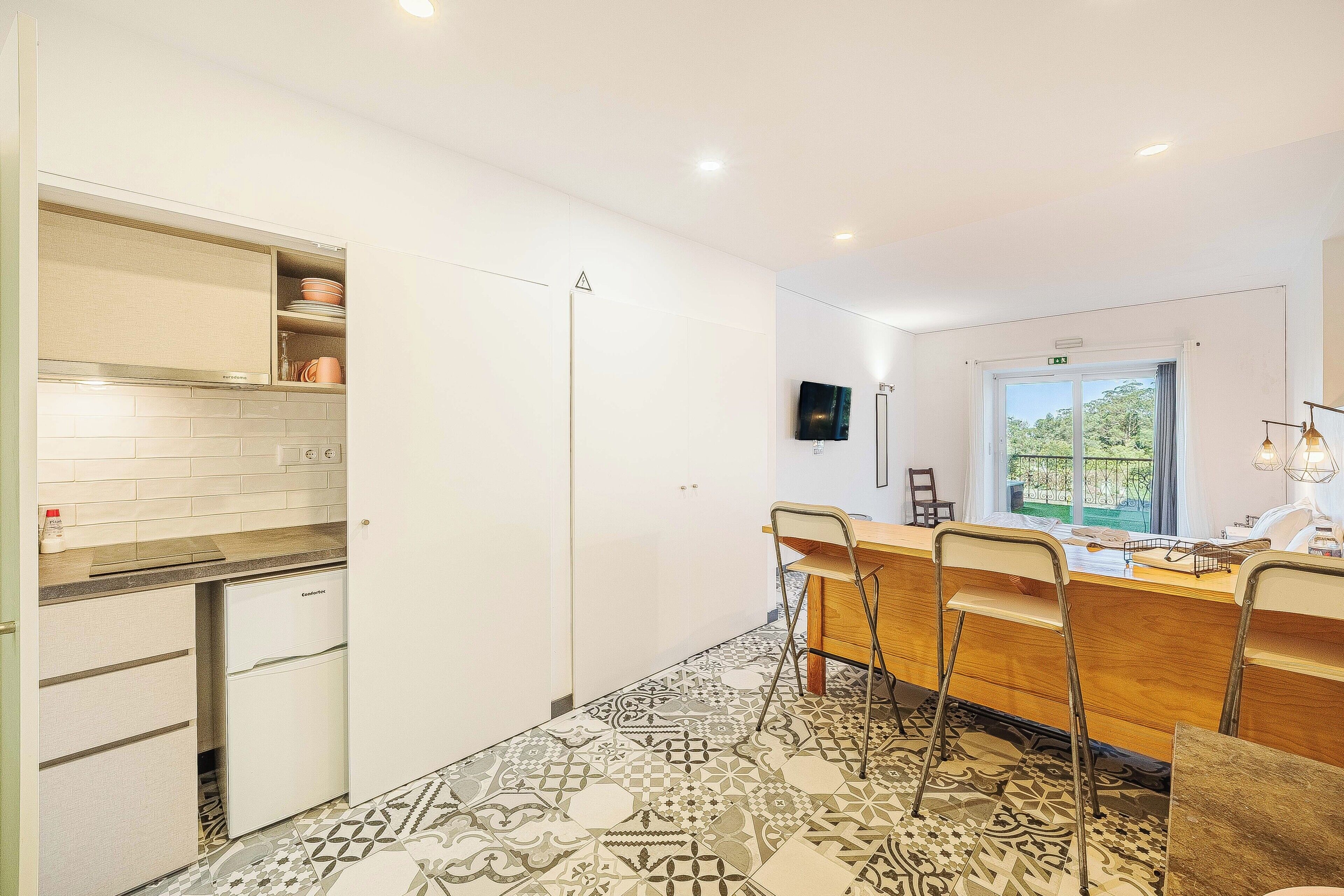 A modern kitchen with white cabinets, a built-in oven, and a patterned floor.
