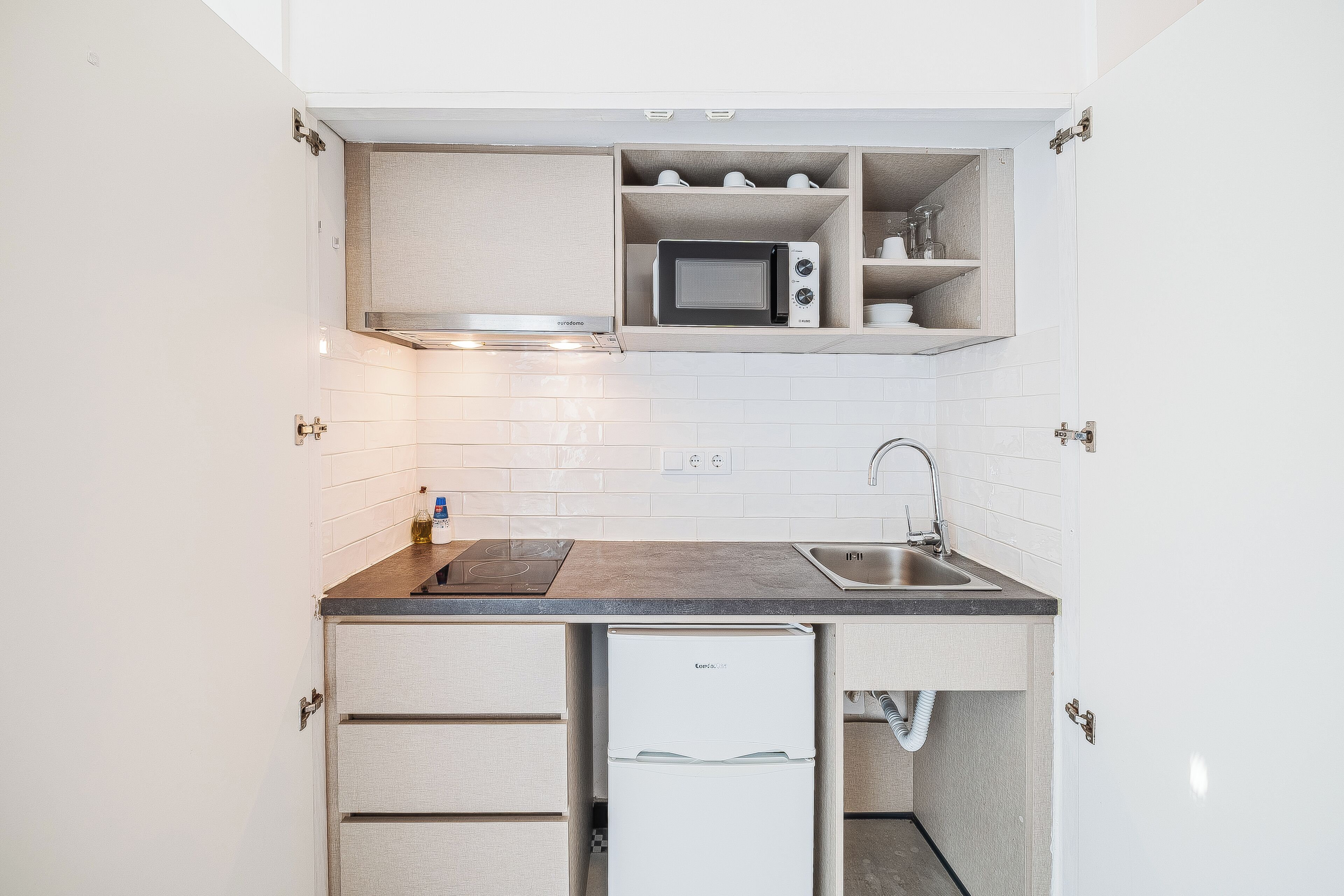 Una cocina compacta con microondas, pileta y alacenas integradas.