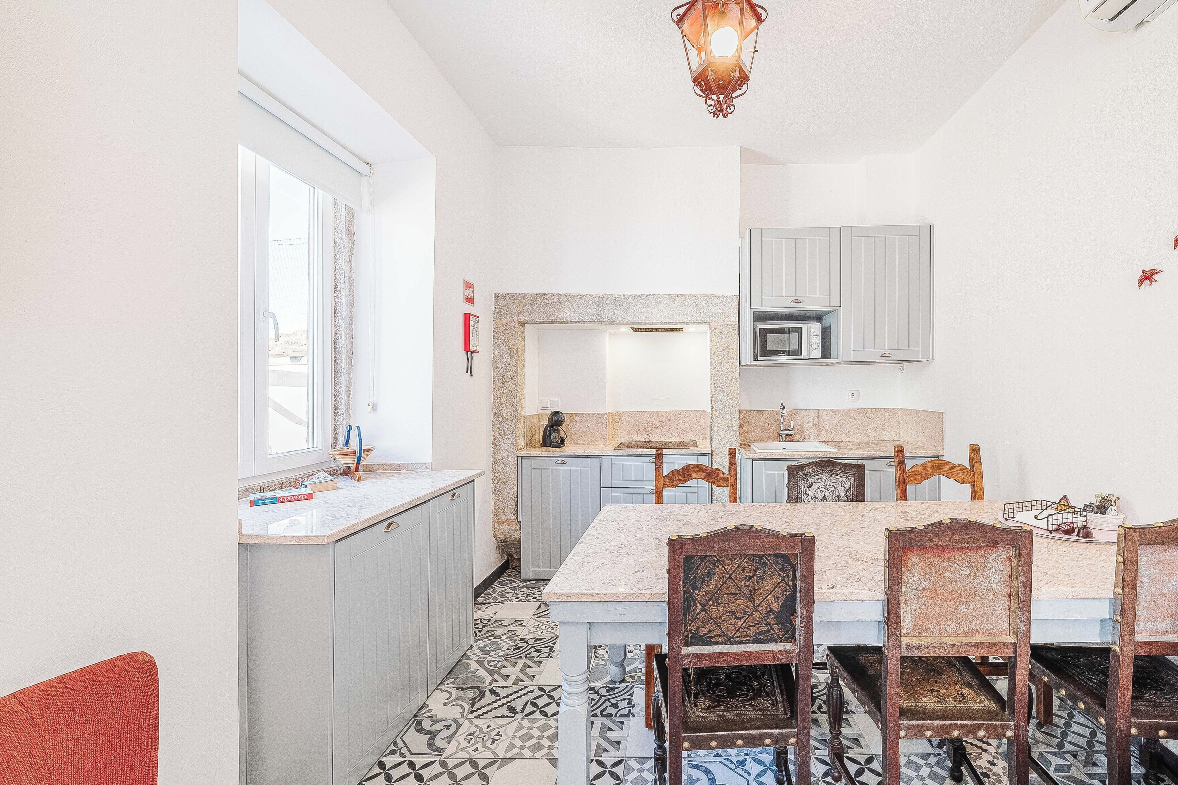 A compact kitchen with a dining area, a window, and a patterned floor.