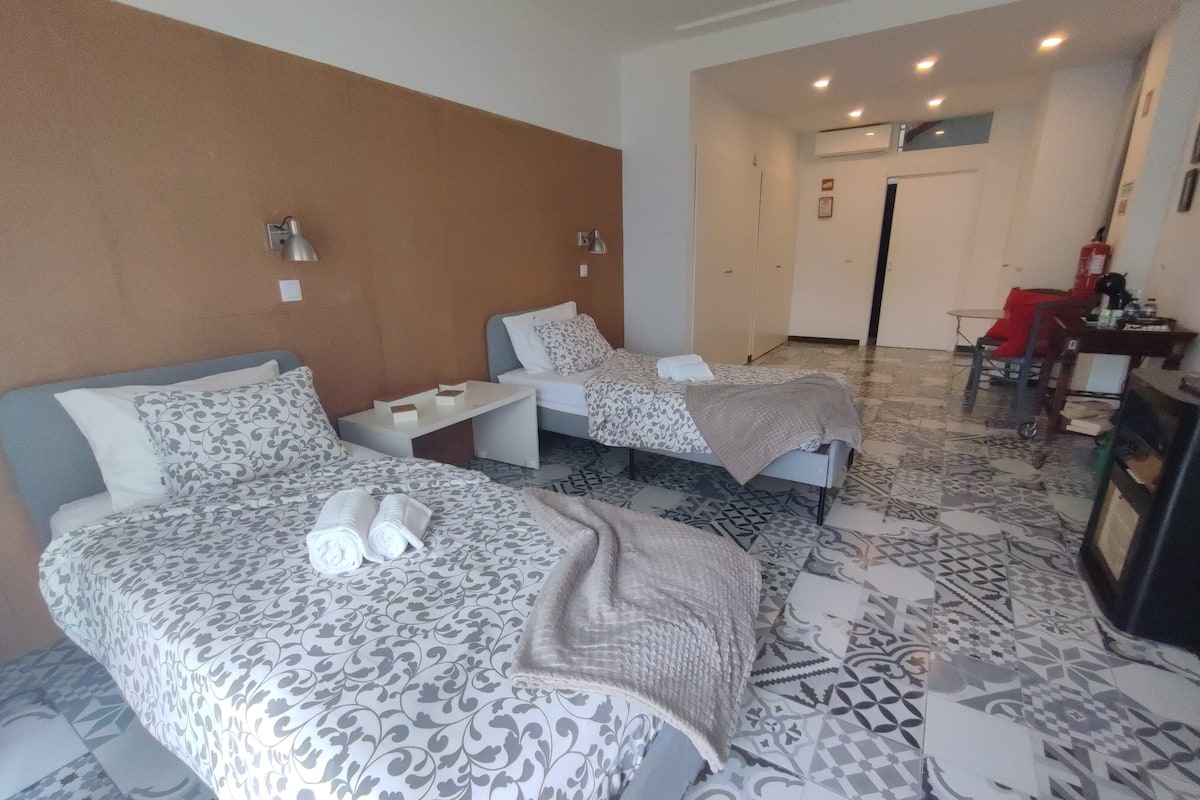Una habitación de hotel con dos camas, una mesita y un televisor.