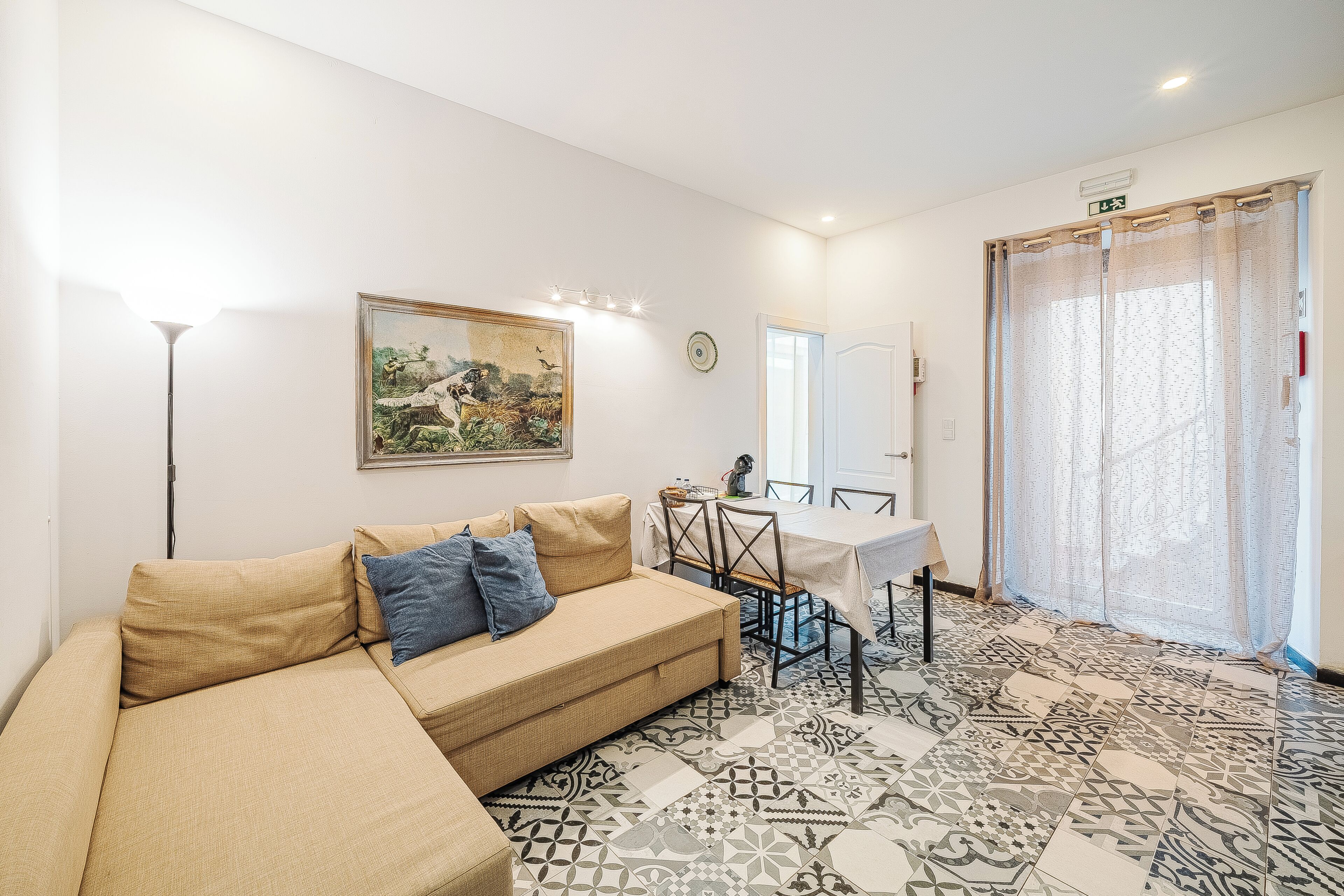 Una sala de estar con sofá, una mesa de comedor y un piso con estampado.