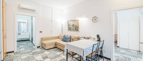 Una habitación con una mesa de comedor, un sofá, baldosas de suelo estampadas y un equipo de aire acondicionado.