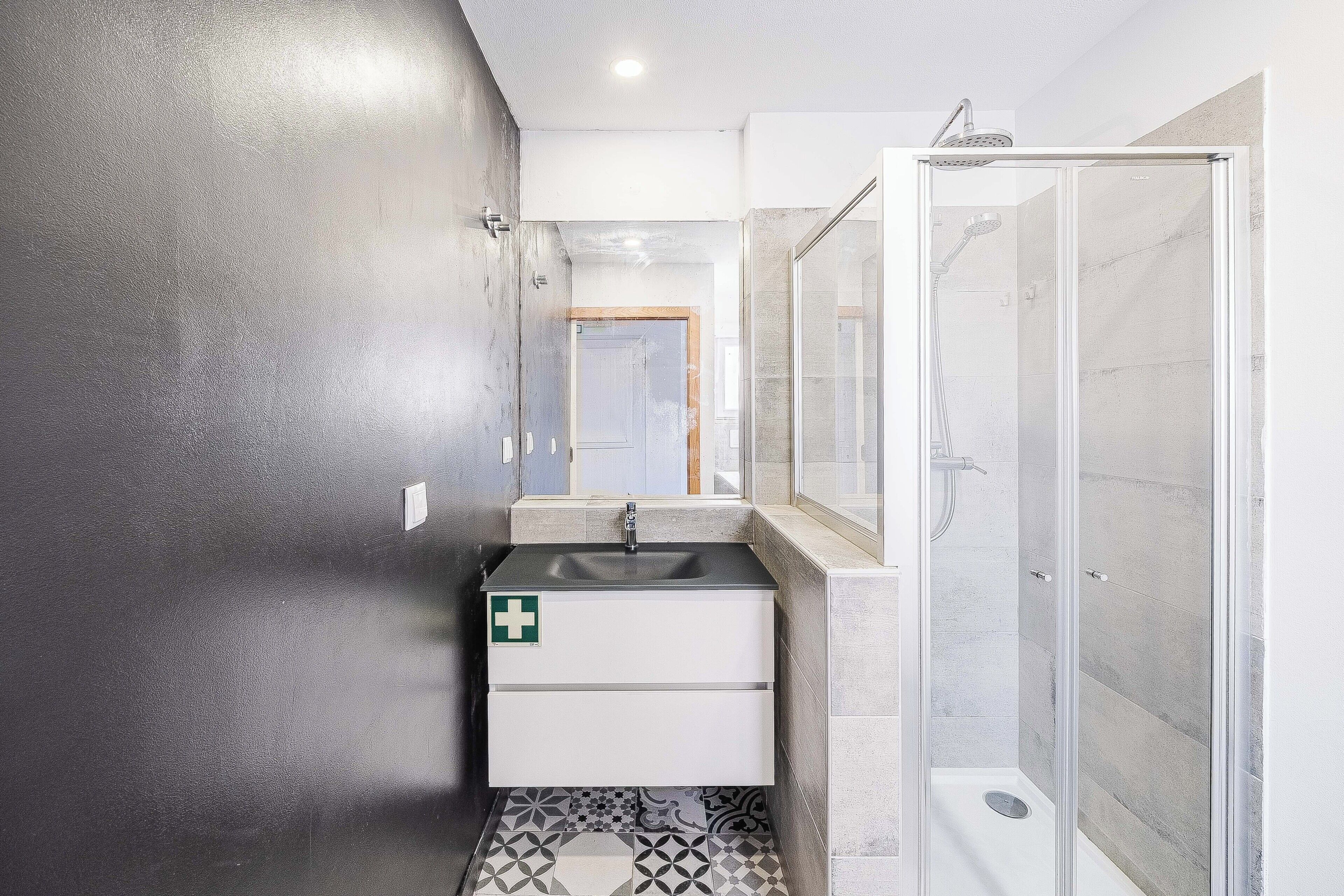 A bathroom with a shower, a sink, and a mirror.